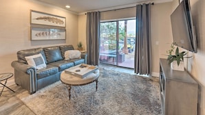 A modern living room with a leather sofa, a coffee table, and a large window with curtains. - Walk to Beach: Lake Havasu Condo w/ Pool Access (Lake Havasu City)