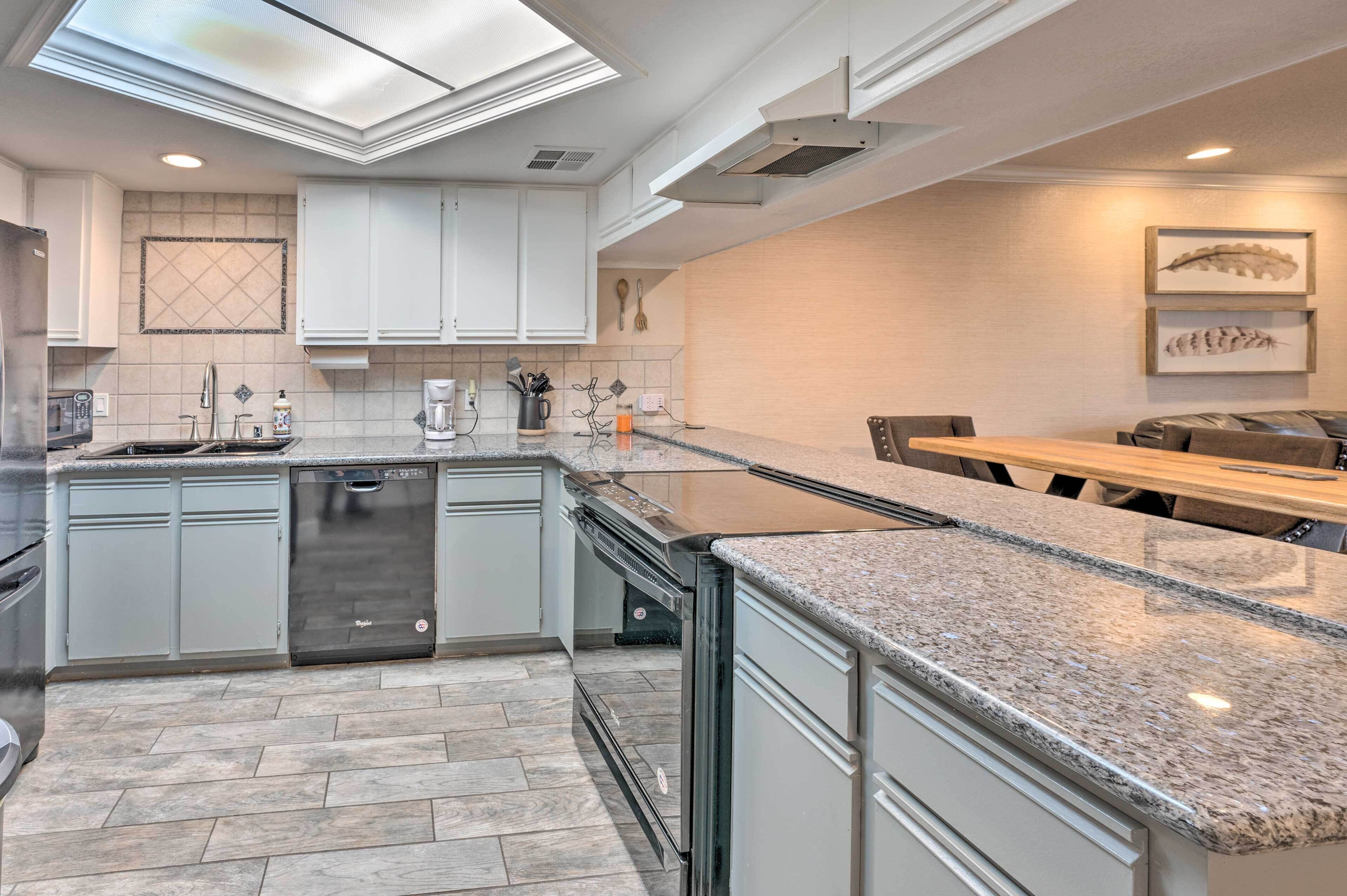 A modern kitchen with grey cabinets, a dishwasher, and a granite countertop.