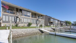 Ein mehrgeschossiges Hotel mit Balkonen, einer Flagge und einem Steg, der sich über das Wasser erstreckt.