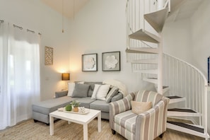 A living room with a grey sofa, striped armchair, white coffee table, and a white spiral staircase. - Charming Condo on Lake Erie w/ Community Pool (Oak Harbor)