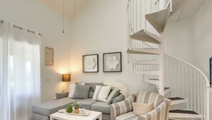 Ein modernes Wohnzimmer mit einem grauen Sofa, einem gestreiften Sessel, einem weißen Couchtisch und einer Wendeltreppe.
