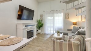 Ein modernes Wohnzimmer mit Kamin, einem an der Wand befestigten Flachbildfernseher, einer Couch und einem gestreiften Sessel.