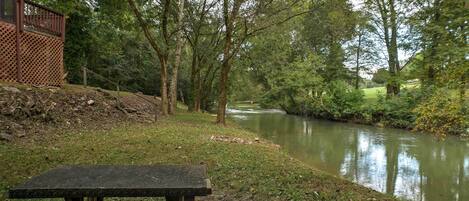 A riverside bench with a view of a calm river and trees.