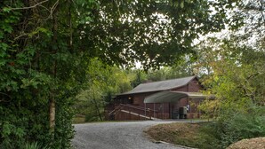 A rustic cabin with a gravel driveway, surrounded by dense foliage. - Creekfront Cabin Near Chattanooga w/ Hot Tub! (Ooltewah)