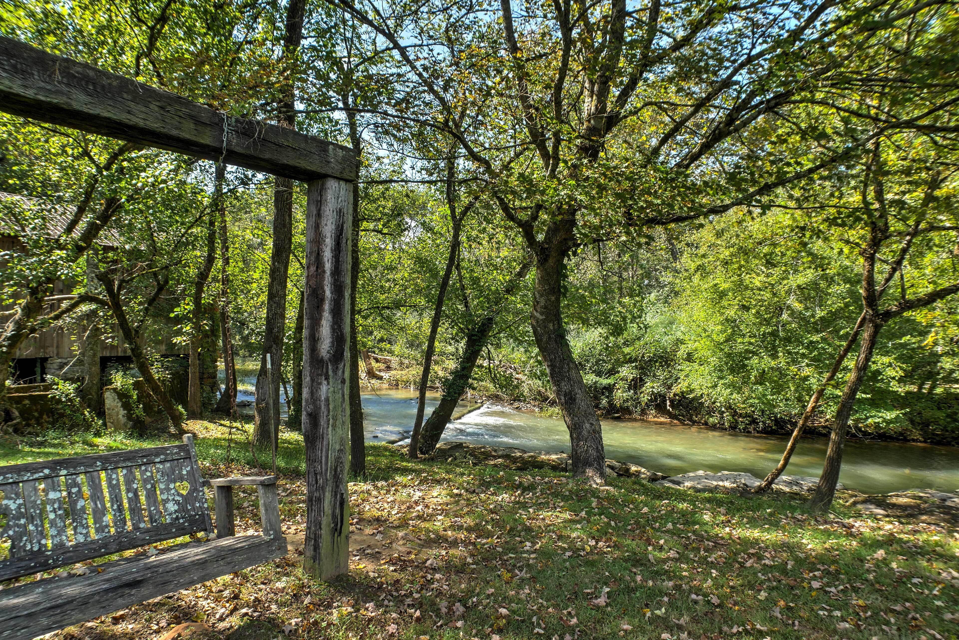 Un banc en bois et une structure en bois, situés dans une zone boisée près d’une rivière.