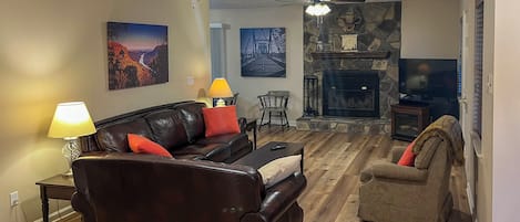 A living room with a fireplace, leather sofa, and a television.