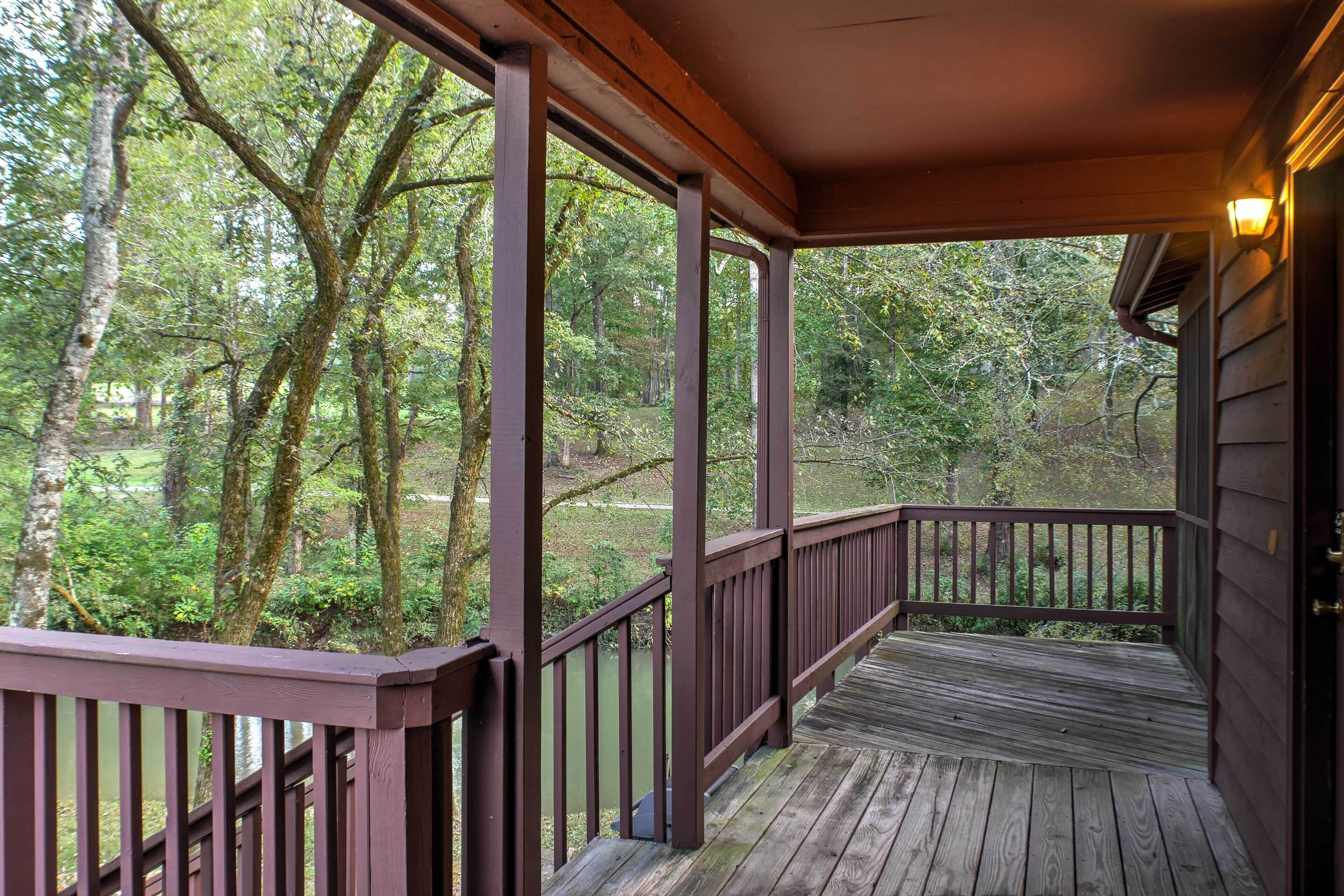 A wooden deck with railings overlooking a forested area.