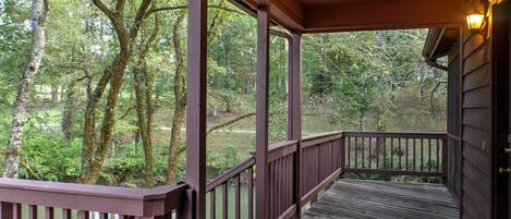 A wooden deck with railings overlooking a forested area.