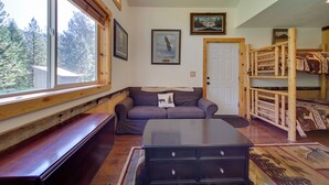 Um quarto aconchegante com um banco de madeira, um sofá, uma cama beliche e uma mesa.