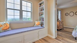 A room with a built-in bench with storage drawers, a bookshelf, and a window with a view of trees. - 'fox Ridge Farmhouse' - Hill Country Getaway! (San Marcos)
