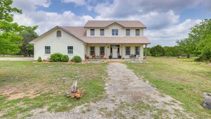 A two-story house with a front porch, a gravel driveway, and a lawn. - 'fox Ridge Farmhouse' - Hill Country Getaway! (San Marcos)