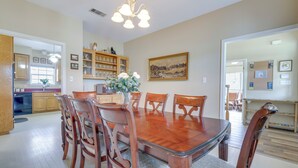 A dining room with a wooden table and chairs, a chandelier, and a painting on the wall. - 'fox Ridge Farmhouse' - Hill Country Getaway! (San Marcos)