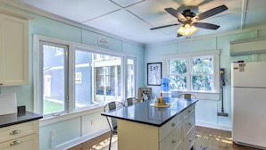 A kitchen with a central island, white cabinetry, and a ceiling fan. - Crystal Lake Cottage: Kayaks & Fire Pit! (Plymouth)
