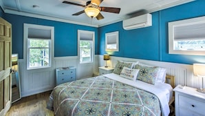 A bedroom with a bed, bedside tables, a ceiling fan, and windows with blinds. - Crystal Lake Cottage: Kayaks & Fire Pit! (Plymouth)