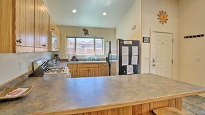 A kitchen with wooden cabinets, a granite countertop, a refrigerator, and a window with a view. - Moab Townhome w/ Pool Access + Stunning Mtn Views! (Moab)