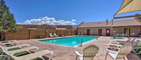 A pool area with lounge chairs, a pool, and a wooden fence.