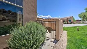 A building with a large glass window, a metal gate, and a well-maintained lawn. - Moab Townhome w/ Pool Access + Stunning Mtn Views! (Moab)