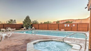 A swimming pool with a hot tub, lounge chairs, and a wooden fence. - Moab Townhome w/ Pool Access + Stunning Mtn Views! (Moab)