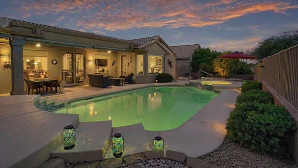 A backyard with a swimming pool, patio furniture, and a covered outdoor seating area. - Sun City Grand Golf Course Gem w/ Pool, Spa & Cart (Surprise)