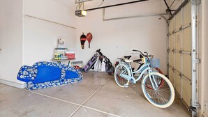 A garage with a bicycle, a blue sofa, and a wall-mounted paddleboard. - Sun City Grand Golf Course Gem w/ Pool, Spa & Cart (Surprise)
