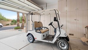 A golf cart parked inside a garage with a wooden door and a concrete floor. - Sun City Grand Golf Course Gem w/ Pool, Spa & Cart (Surprise)
