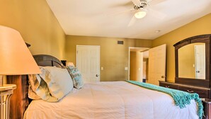 A bedroom with a bed, a nightstand, a lamp, a ceiling fan, and a door. - Condo w/ Pool Access, 8 Mi to Phoenix Mtn Preserve (Phoenix)