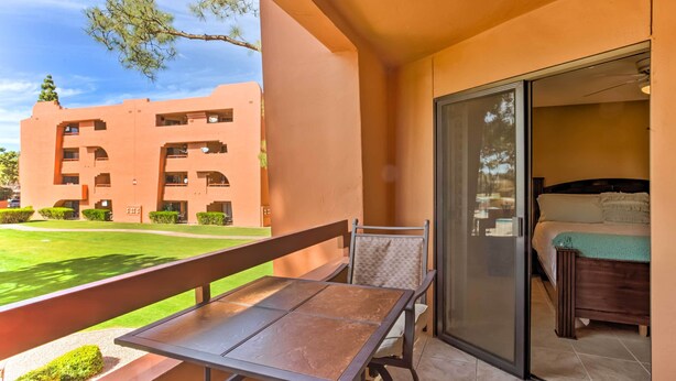 A balcony with a table and chairs, a sliding glass door leading to a bedroom with a bed and a green blanket. - Condo w/ Pool Access, 8 Mi to Phoenix Mtn Preserve (Phoenix)