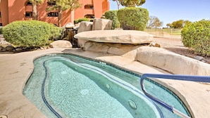 A swimming pool with clear water, surrounded by rocks and bushes, with a building in the background. - Condo w/ Pool Access, 8 Mi to Phoenix Mtn Preserve (Phoenix)