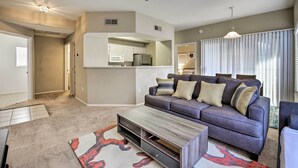 A modern living room with a grey sofa, a coffee table, and a kitchen area in the background. - Condo w/ Pool Access, 5 Mi to Tempe Diablo Stadium (Tempe)