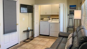 A compact living space with a kitchenette, a black leather sofa, and a tiled floor.