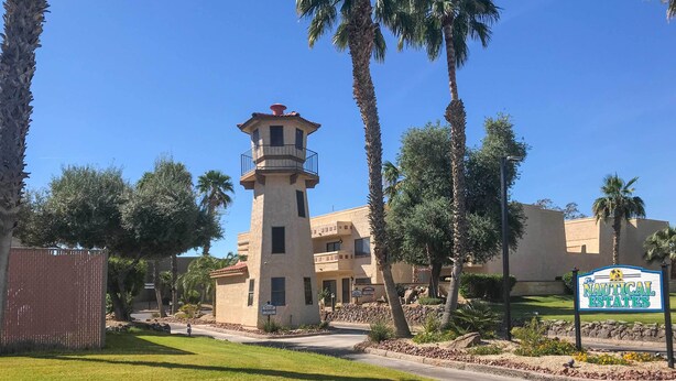 A building with a tower, palm trees, and a sign for 'The Nautical Estates'.