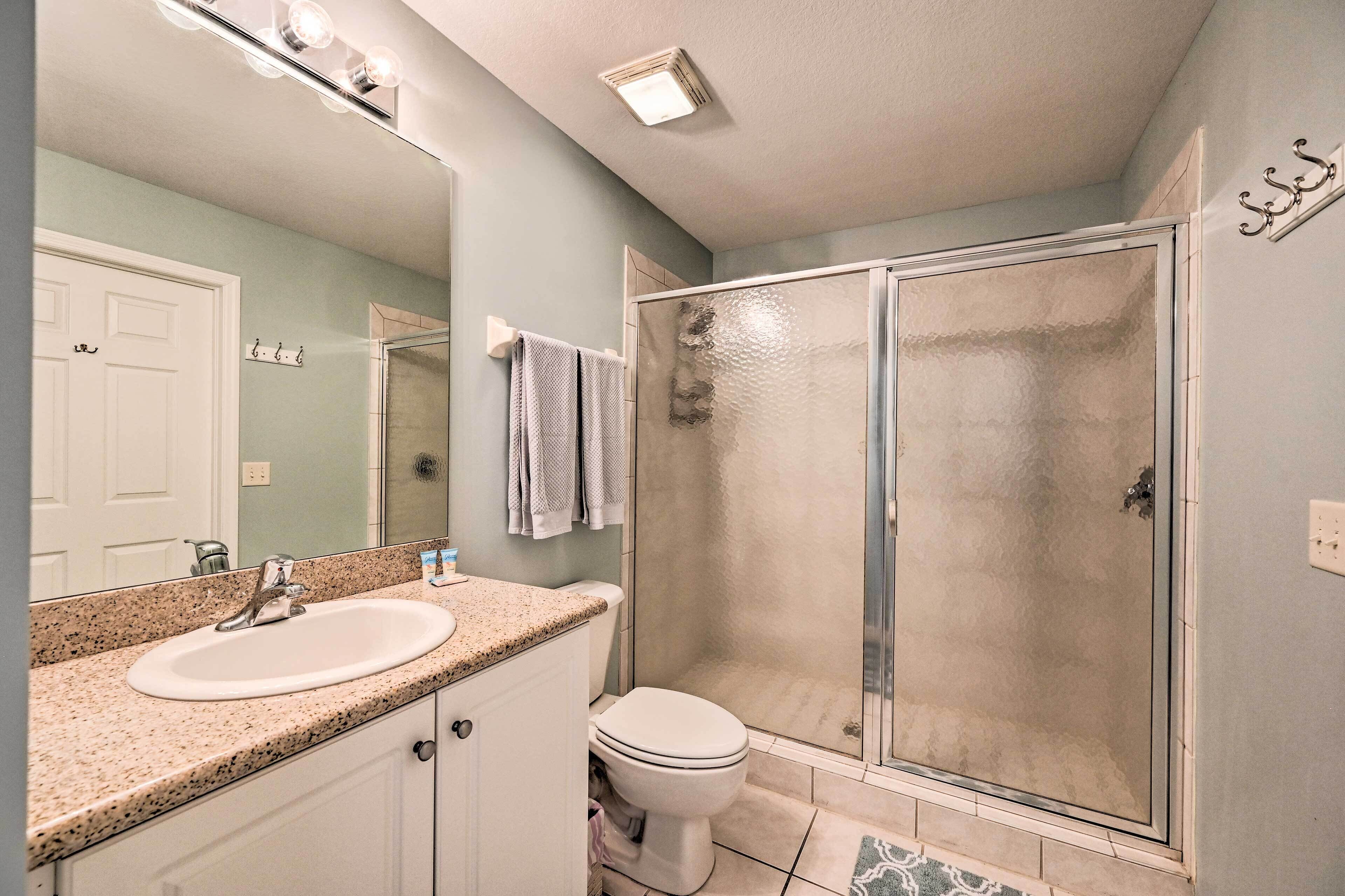 A bathroom with a sink, toilet, and glass shower enclosure.