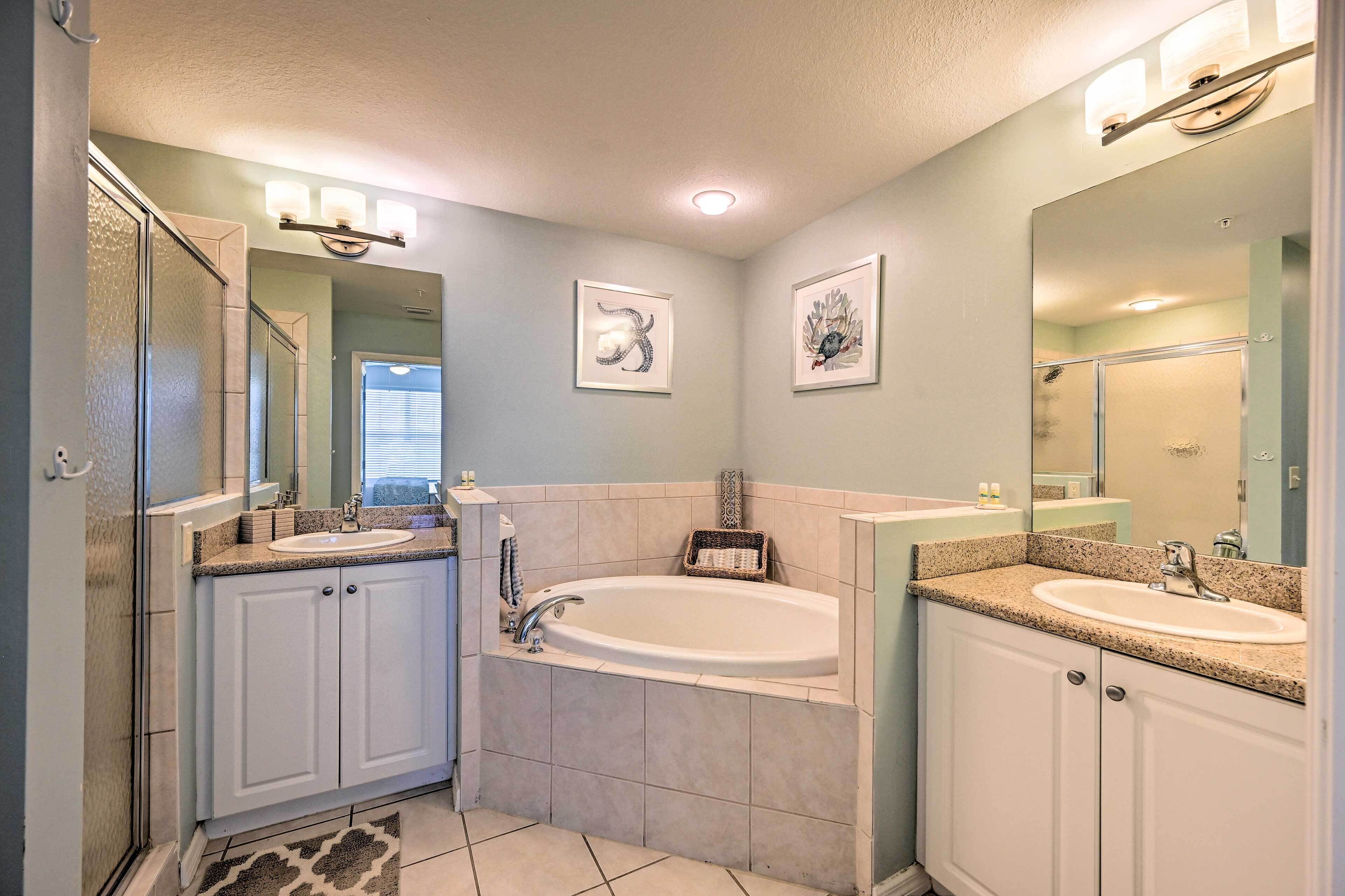 A bathroom with a bathtub, two sinks, and a shower.