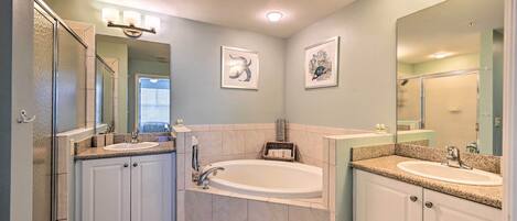A bathroom with a bathtub, two sinks, and a shower.