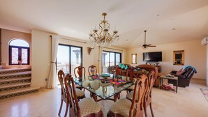 Un'ampia sala da pranzo con tavolo in vetro, sedie in legno e lampadario.