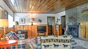 A cozy living room with a plaid sofa, a television, and a fireplace. - Ruidoso Log Cabin Near Skiing & Wildlife! (Ruidoso)