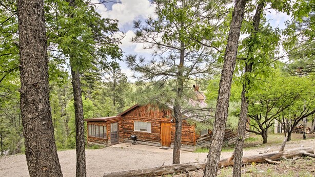 A rustic log cabin with a wooden door and windows, surrounded by trees and a gravel driveway. - Ruidoso Log Cabin Near Skiing & Wildlife! (Ruidoso)