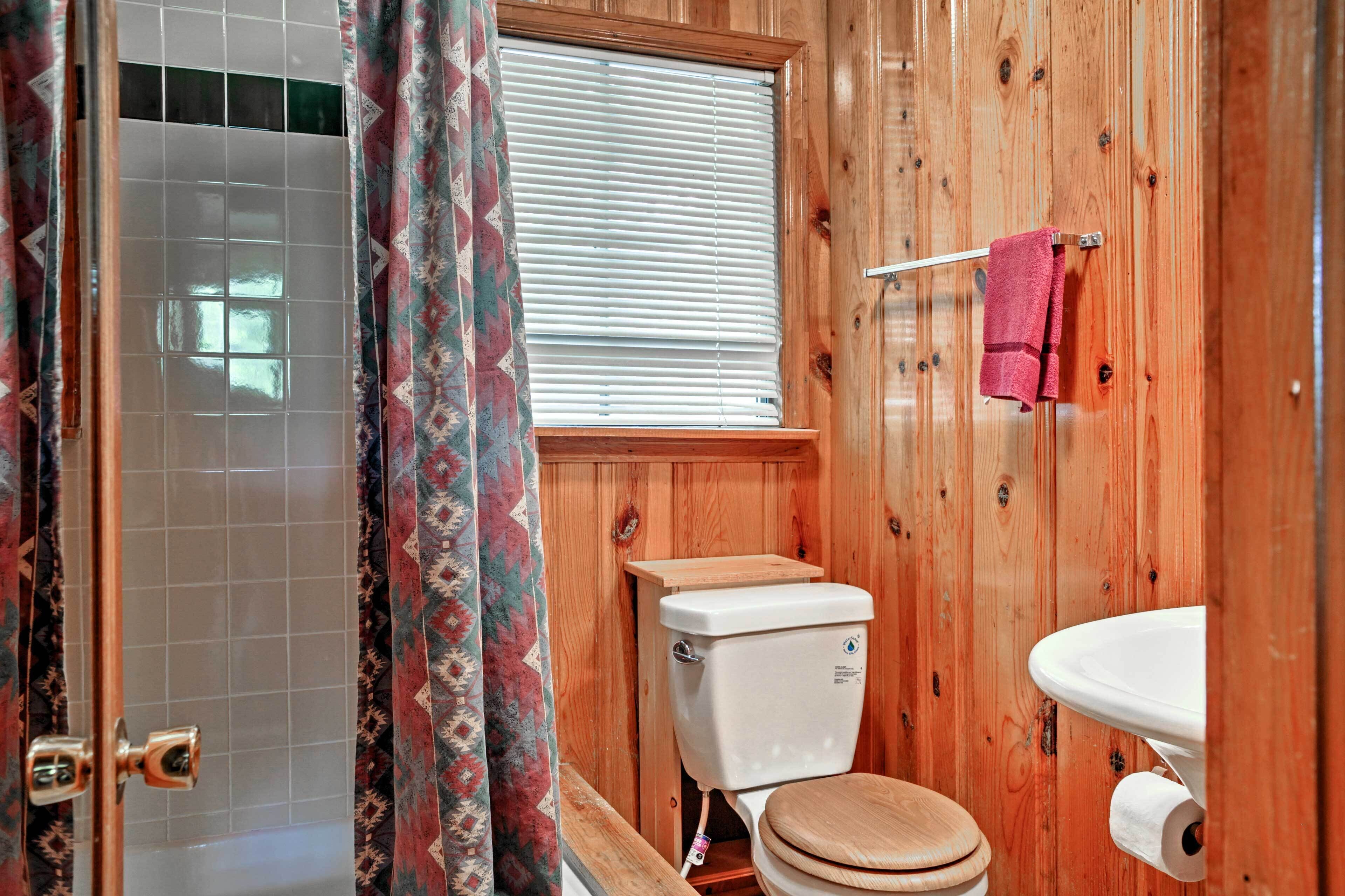 A wooden bathroom with a toilet, sink, and shower.