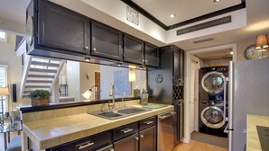 A modern kitchen with dark cabinetry, a double sink, and a built-in washing machine. - North Phoenix Gem w/ Courtyard & Pool Access (Phoenix)