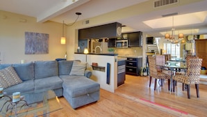A modern living room with a grey sectional sofa, a glass coffee table, and a dining area with patterned chairs. - North Phoenix Gem w/ Courtyard & Pool Access (Phoenix)