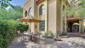 A patio with a table and chairs, surrounded by potted plants and a building with arched windows. - North Phoenix Gem w/ Courtyard & Pool Access (Phoenix)