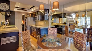 A modern kitchen with a central island, a dining area with a glass table, and a bar area with a sign. - North Phoenix Gem w/ Courtyard & Pool Access (Phoenix)