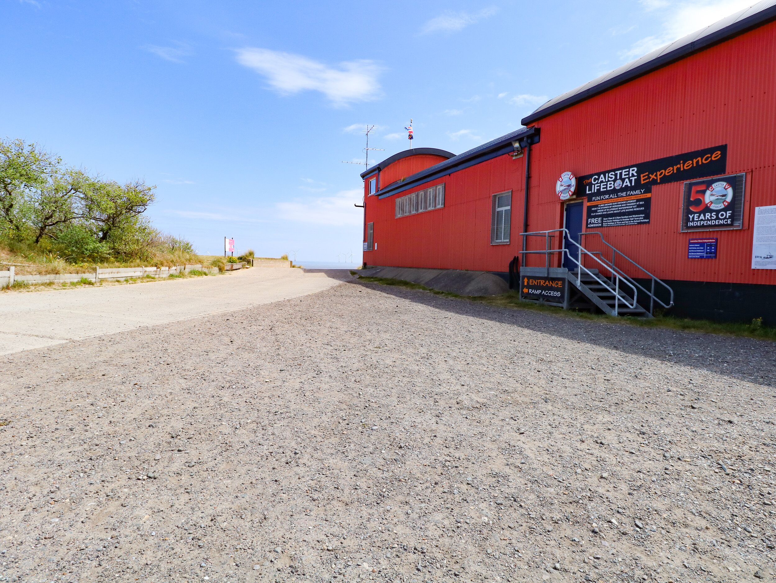A red building with a sign reading "CAISTER LIFEBOAT Experience" and "5 years of Independence".