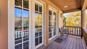A covered porch with a wooden deck, large sliding glass doors, and outdoor seating.