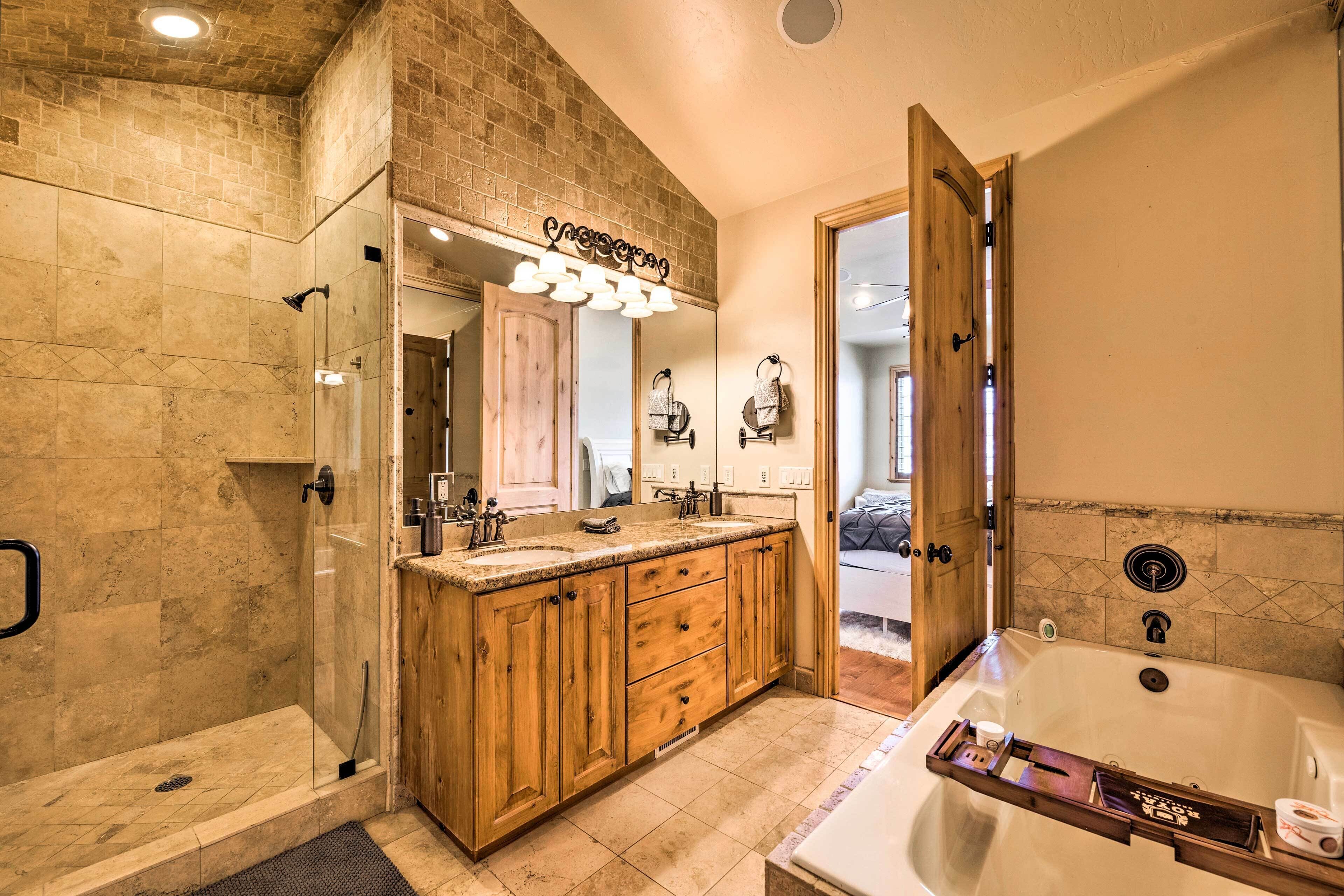A bathroom with a glass-enclosed shower, wooden vanity with a mirror, and a large bathtub.