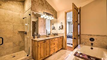 A bathroom with a glass-enclosed shower, wooden vanity with a mirror, and a large bathtub.