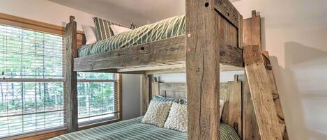 A bunk bed with a wooden headboard, a window with blinds, and a ceiling light fixture.