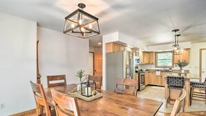 A modern kitchen with wooden cabinets, a central island, and a dining area with a wooden table and chairs.