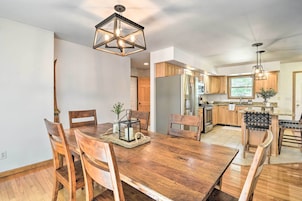 Una cocina moderna con armarios de madera, una isla central y un comedor con mesa y sillas de madera.