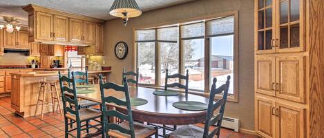 A kitchen with wooden cabinets, a dining table with chairs, and a large window.